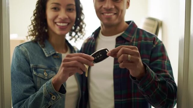 Happy Diverse Couple Holding Car Keys in Doorway, New Home or Vehicle Ownership