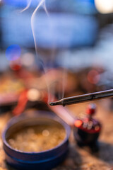 A close-up view of a soldering iron emitting smoke, surrounded by various tools and materials on a workbench, showcasing the intricate details of the process. neutral background, clear negative space