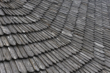 A close-up view of a traditional wooden shingle roof showcasing the intricate arrangement of overlapping shingles in a wavy pattern. neutral background, clear negative space, clean composition