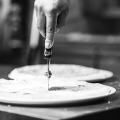 Closeup of round shape stainless steel cutter wheel cutting piece of white pizza