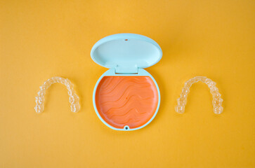 Clear Dental Aligners and Case on Orange Background. Orthodontic Mouthpieces.