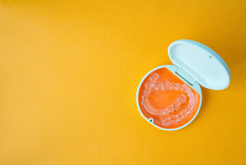 Clear Dental Aligners and Case on Orange Background. Orthodontic Mouthpieces.