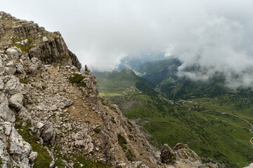 Mountain landscape with green hills, rocky cliffs, and cloudy sky