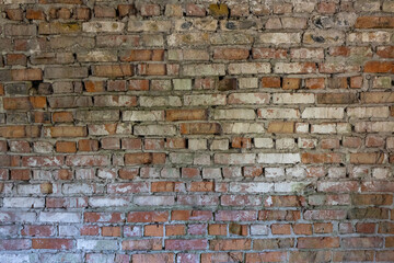A close-up view of an aged brick wall showcasing a variety of colors and textures, with some bricks appearing worn and weathered over time. The wall features a mix of red, brown, and gray bricks,