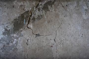 Close-up view of a weathered concrete wall showing cracks and peeling paint, highlighting the texture and imperfections of the surface. neutral background, clear negative space, clean composition