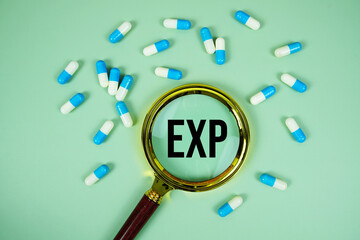 Expiration Date of Medicament with magnifying glass and medicine capsule on green background