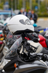 Closeup white moto helmet on motorcycle handlebars against blurred background