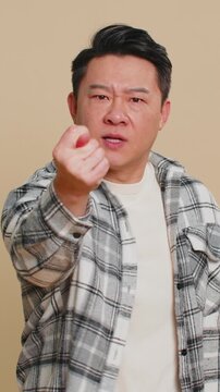 Angry aggressive Asian middle-aged man showing fig negative gesture, you dont get it anyway. Rapacious, avaricious, acquisitive. Body language. Refusal fig sign. Greedy frustrated mature Chinese guy.