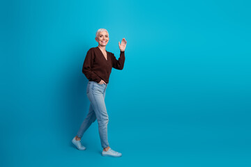 Stylish woman walking confidently in casual outfit on a vivid blue background, showcasing fashion and positivity