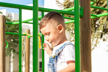 Obraz premium Portrait of a little Hispanic boy wearing overalls walking in an outdoor playground in Neiva, Huila, Colombia. A concept of child development