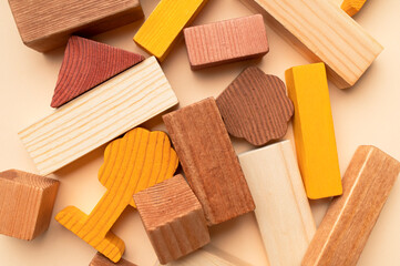 Wooden children's construction set blocks of different shapes natural colors on beige background. Montessori style cubes game for toddlers flat lay top view. Concept of learning and education