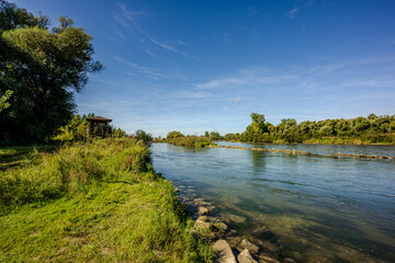 Ruhige Flusslandschaft mit Ufervegetation und klarem Himmel an einem sonnigen Tag