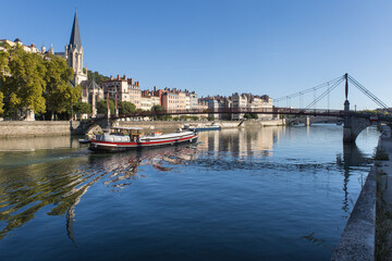 La Saône avec un bateau de croisière et vue sur l'église Saint-georges du vieux Lyon, la colline de Fourvière et les quais de Saône en été