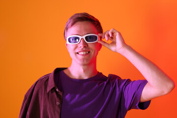 Smiling man wearing sunglasses in neon lights against orange background
