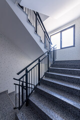 Obraz premium Modern stair case between floors. Stairs with metallic rail in modern building. Interior of a contemporary apartment or office building. Architecture and real estate background.