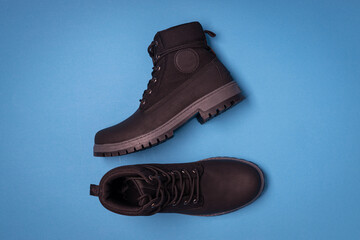 Men's black boots. Stylish winter shoes, blue background