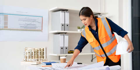 Site Engineer woman working with drawings inspection at desk in site office .Engineering tools and construction concept.