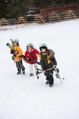 Young skiers embark on a snowy adventure in a winter wonderland surrounded by pine trees and wooden ski racks at a picturesque mountain resort