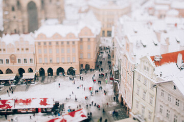 A beautiful winter scene of a snow-covered city square bustling with cheerful crowds, capturing the essence of a festive holiday atmosphere.