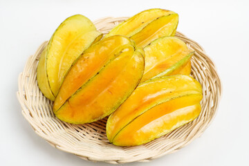 Fresh ripe starfruit (carambola) arranged in a natural woven basket on clean white background, tropical exotic fruit concept for healthy organic lifestyle.