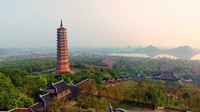 Panoramic view of Ninh Binh at sunset with pagoda and lush landscapes.