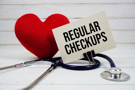 Regular Checkups text message on paper card with stethoscope on wooden background