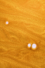 Golden cosmetic shimmer liquid lotion gel illuminator texture smudge swatch on white background