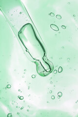 Green colored transparent serum swatch and glass pipette dropper. Beauty product sample swatch backdrop