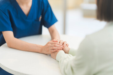 カウンセリングをしている医師が両手で患者の手を包み込んている。