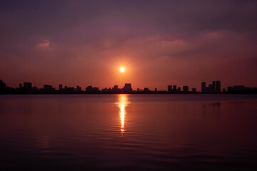 Obraz premium Golden sunset over the lake, silhouetted friends watching the glowing horizon in peaceful harmony.