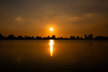 Fototapeta premium Golden sunset over the lake, silhouetted friends watching the glowing horizon in peaceful harmony.