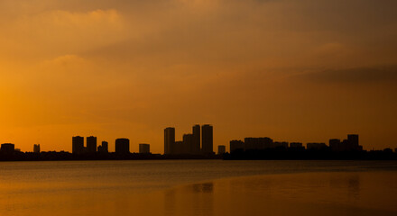 Obraz premium Golden sunset over the lake, silhouetted friends watching the glowing horizon in peaceful harmony.