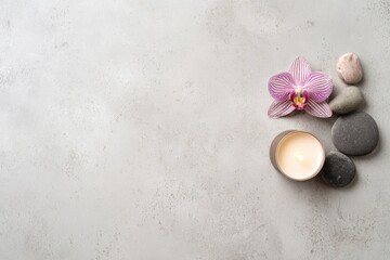 Minimal spa background with orchid flower, lit candle and smooth stones on gray surface, perfect for wellness, relaxation, meditation, skincare and beauty design with copy space