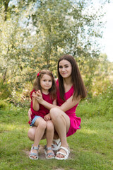 Obraz premium portrait of young mother with a small daughter in summer nature at sunset. Hugs