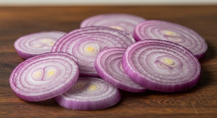Pile of sliced red onions displaying concentric layers on brown wooden surface, showing textures and light
