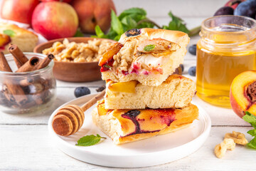 Tasty fruit dessert Focaccia. Sweet viral italian Focaccia open pie, with various seasonal autumn and summer fruits - plum, apple, figs, apricot, blueberry, peach and nuts, with spices and honey
