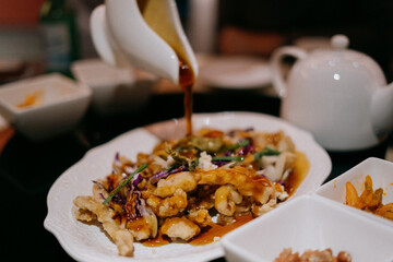 Pouring sauce over sweet and sour pork at a Korean-Chinese restaurant.