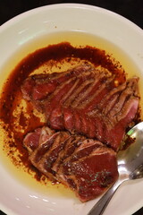 Khun Mee’s fried beef served medium-rare with spicy sauce at Ban Phueng Chom restaurant, Ari, Bangkok, Thailand, on white plate.