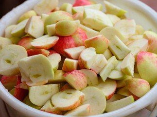 Close-up of a white bucket full of pieces of cutting organic apples