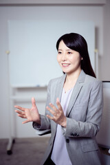 ホワイトボードの前でインタビューに答える女性