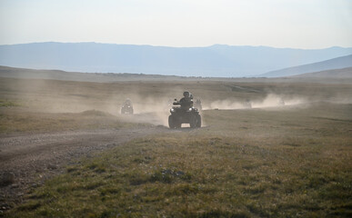 Many quads are driven on dirt roads. Quads are kicking up dust on the mountain. Tourists ride quad bikes. Racing quad bike.