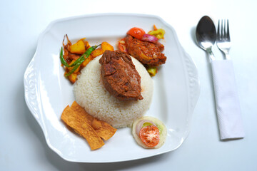 Rice and Curry with Spicy Devil Chicken Served on White Plate. spoon with fork