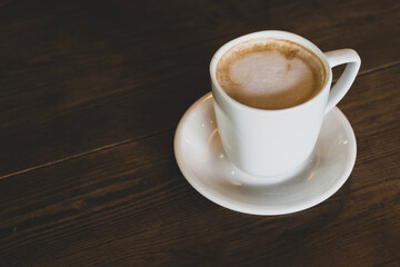 Hot latte coffee in white cup. Cappuccino style latte on table. Cup of latte with frothy milk. Freshly brewed latte with milk foam.