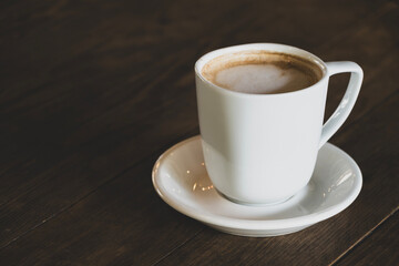 Hot latte coffee in white cup. Cappuccino style latte on table. Cup of latte with frothy milk. Freshly brewed latte with milk foam.