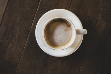 Hot latte coffee in white cup. Cappuccino style latte on table. Cup of latte with frothy milk. Freshly brewed latte with milk foam.