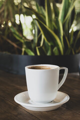 Hot coffee in white mug with dark backdrop. Freshly brewed coffee against black background. Cup of coffee on dark background.