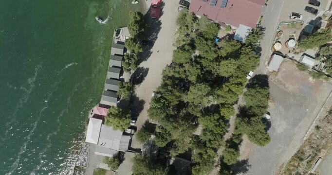 Aerial view of the shoreline near Lake Sevan, with a blend of turquoise water, boats, docks, buildings, and lush greenery, Lake Sevan, Gegharkunik Province, Armenia.
