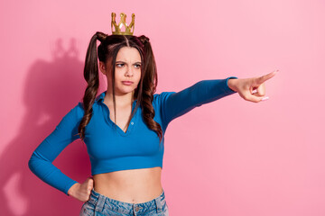 Confident young woman in a trendy outfit making a pointing gesture with a serious expression on a...