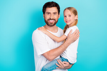 Happy father and daughter embracing in front of a teal background expressing love, joy, and family bonding