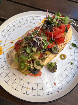 Tostada de hummus, tomate, oliva y berros (almuerzo saludable)